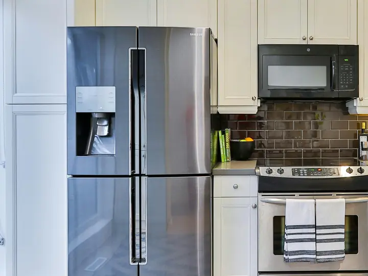 Homeowner using a refrigerator maintenance checklist in a modern kitchen